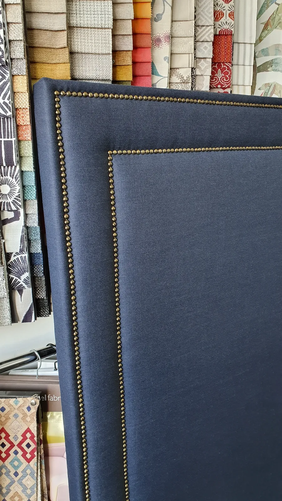 Pair of navy upholstered bedheads finished with brass stud detailing