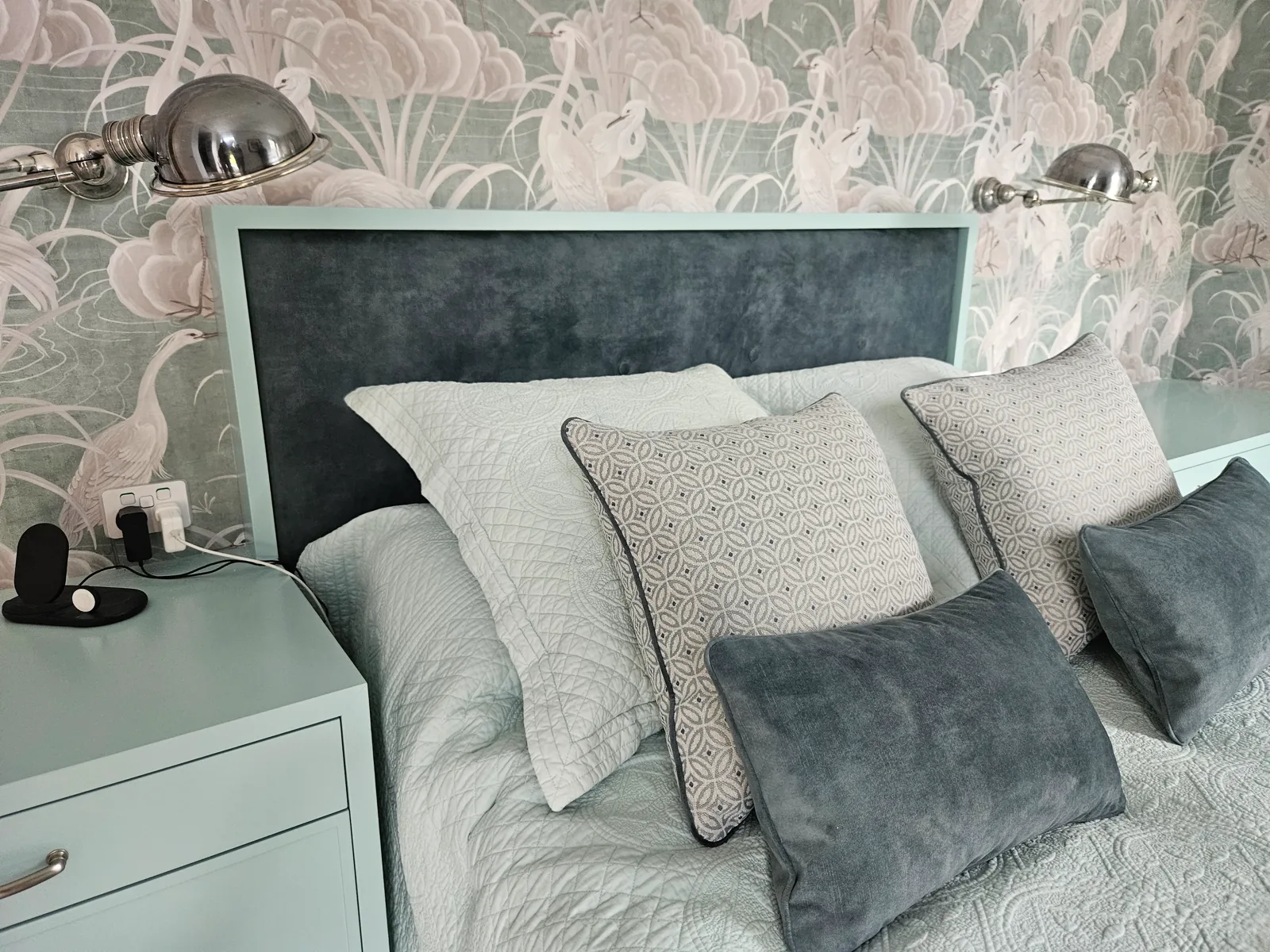 Grey velvet bedhead with cushions in a styled bedroom