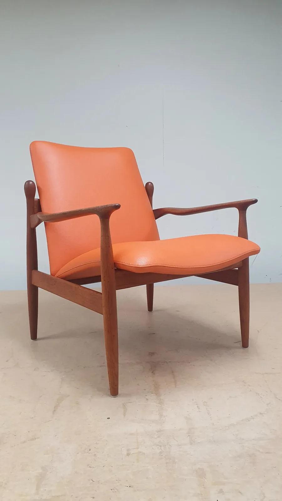 Mid-century orange leather occasional chair with a timber frame