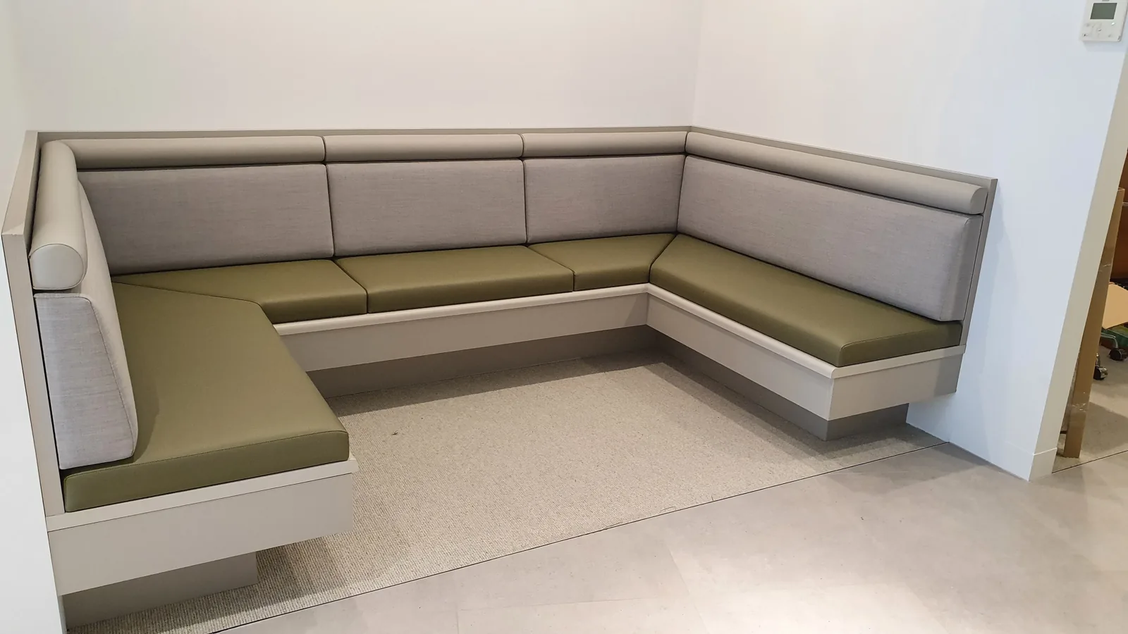 Corner banquette with grey backrests and green seat cushions