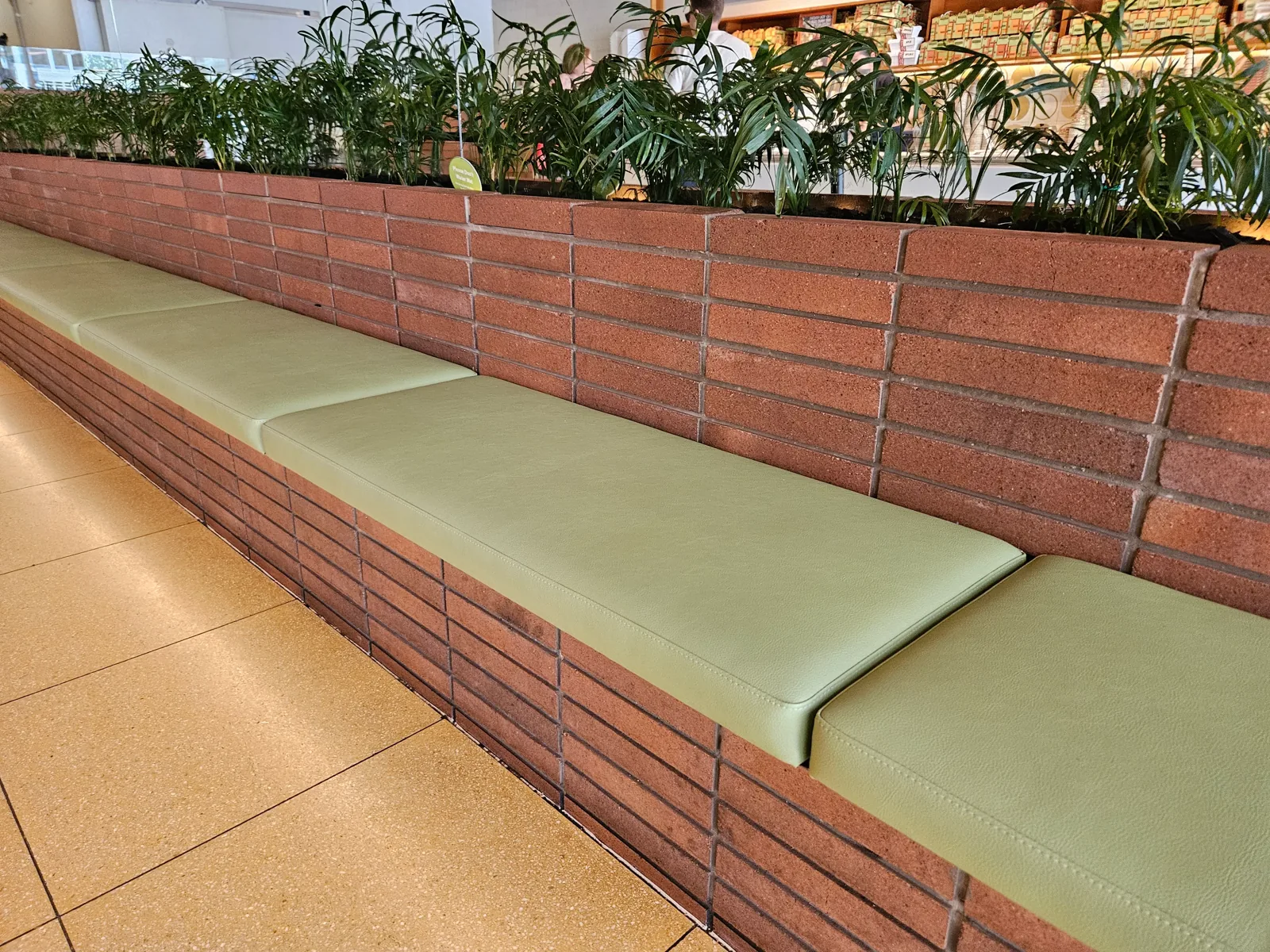 Long green vinyl bench seating along a brick wall in a commercial venue